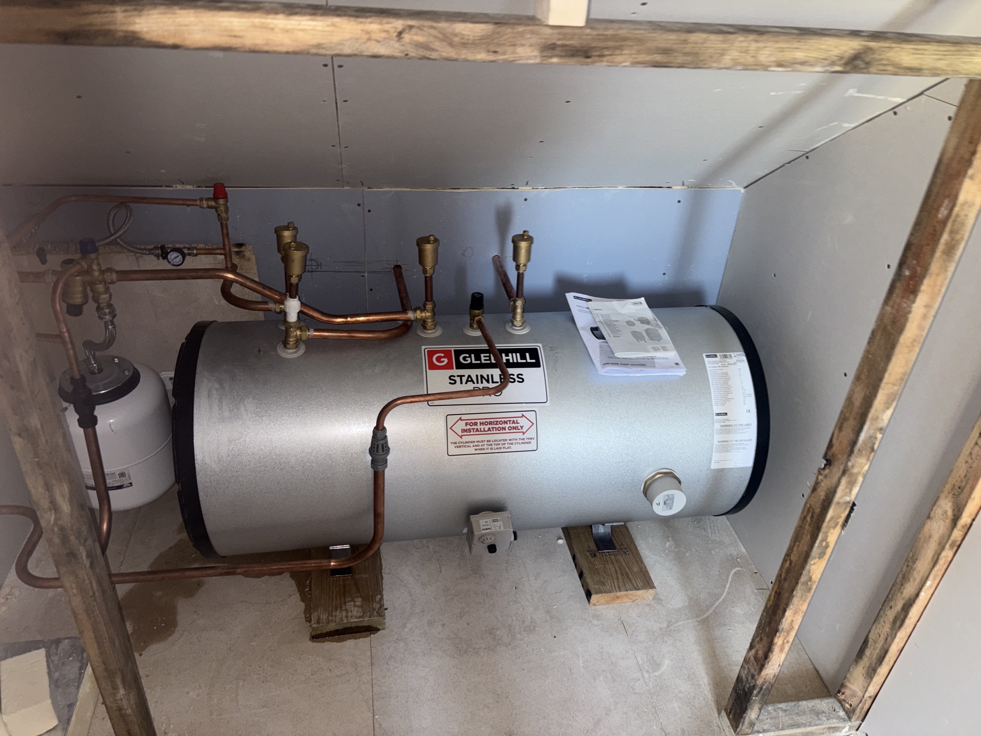 Professional horizontal unvented hot water cylinder installation showing space-saving design